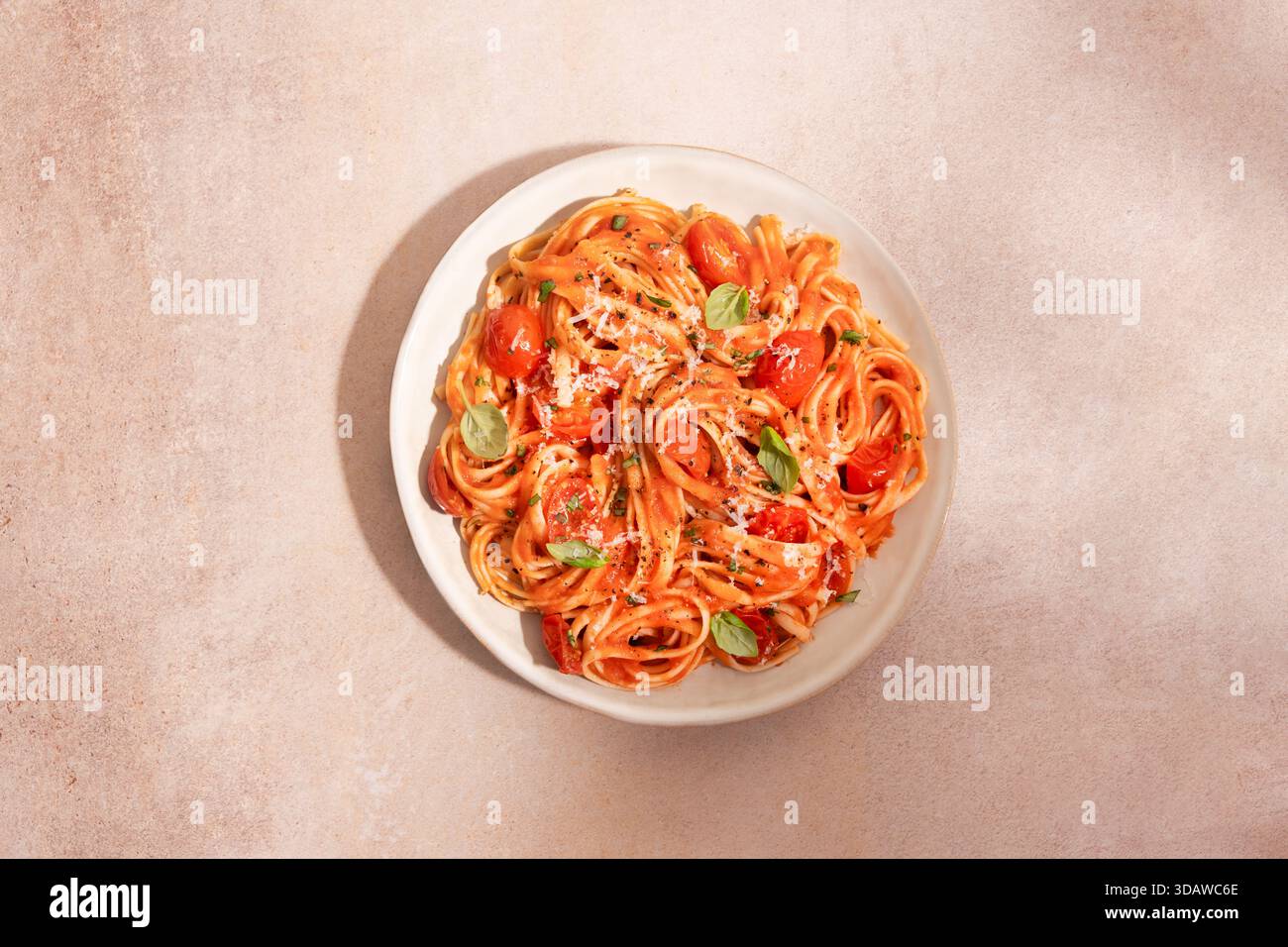Vue de dessus d'une assiette de pâtes spaghetti recouverte d'une riche sauce tomate, garnie de tomates cerises, basilic frais et parmesan râpé sur un texte Banque D'Images