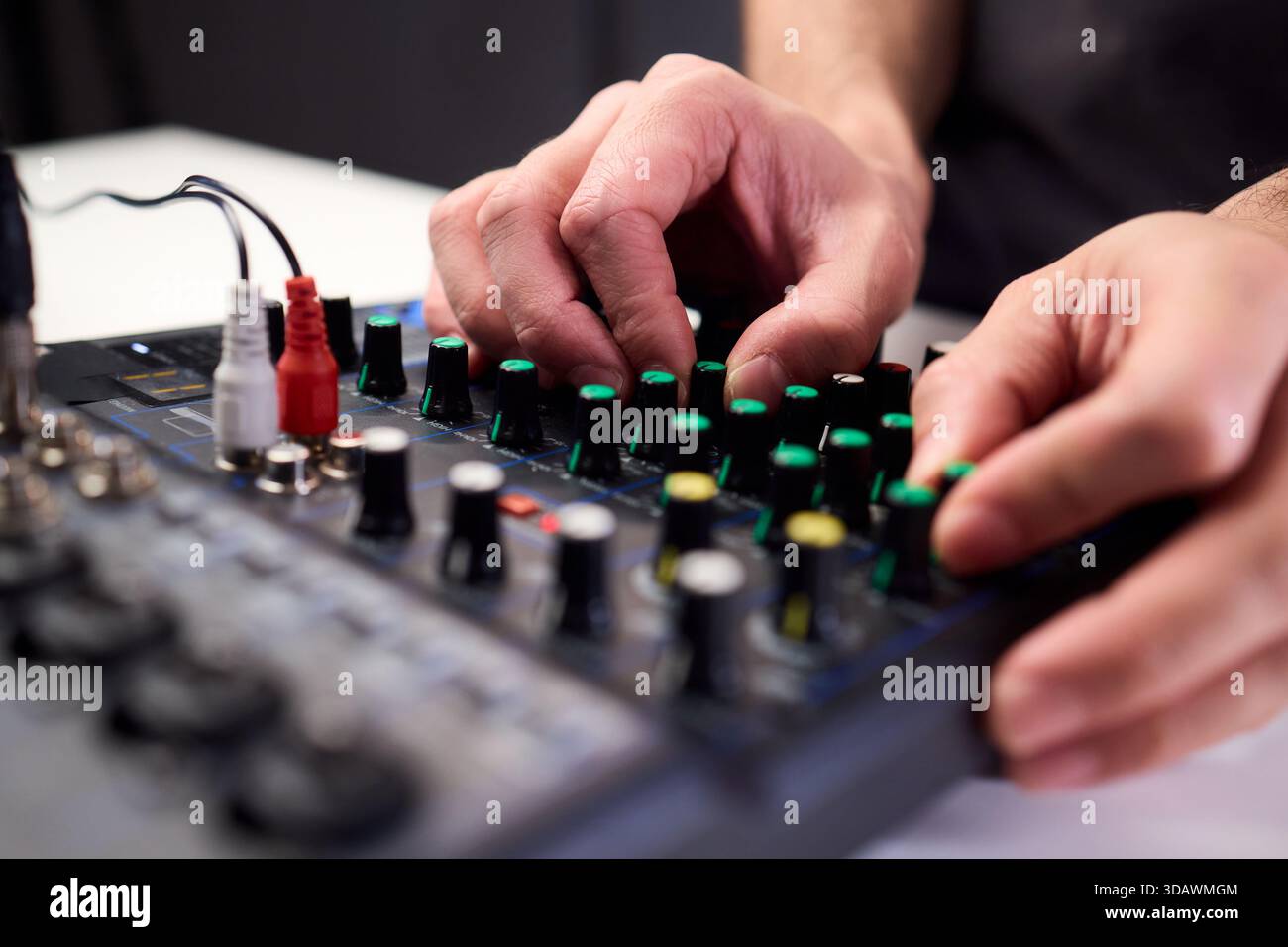 Les doigts tactiles manipulent les cadrans lumineux lors de la configuration de SoundCheck, un technicien professionnel règle l'équipement audio avec plusieurs câbles connectés Banque D'Images