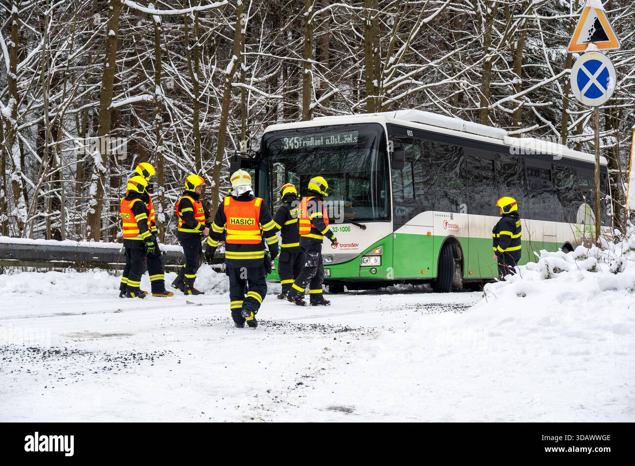 Ostrava, République tchèque - 23.11.2024, des pompiers travaillant pour libérer un bus coincé dans de profondes déneigements sur une route glacée et enneigée, capturant l'hiver c Banque D'Images