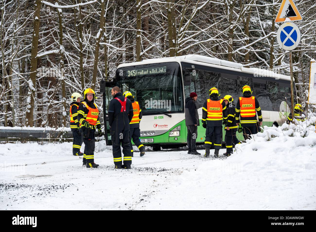 Ostrava, République tchèque - 23.11.2024, des pompiers travaillant pour libérer un bus coincé dans de profondes déneigements sur une route glacée et enneigée, capturant l'hiver c Banque D'Images