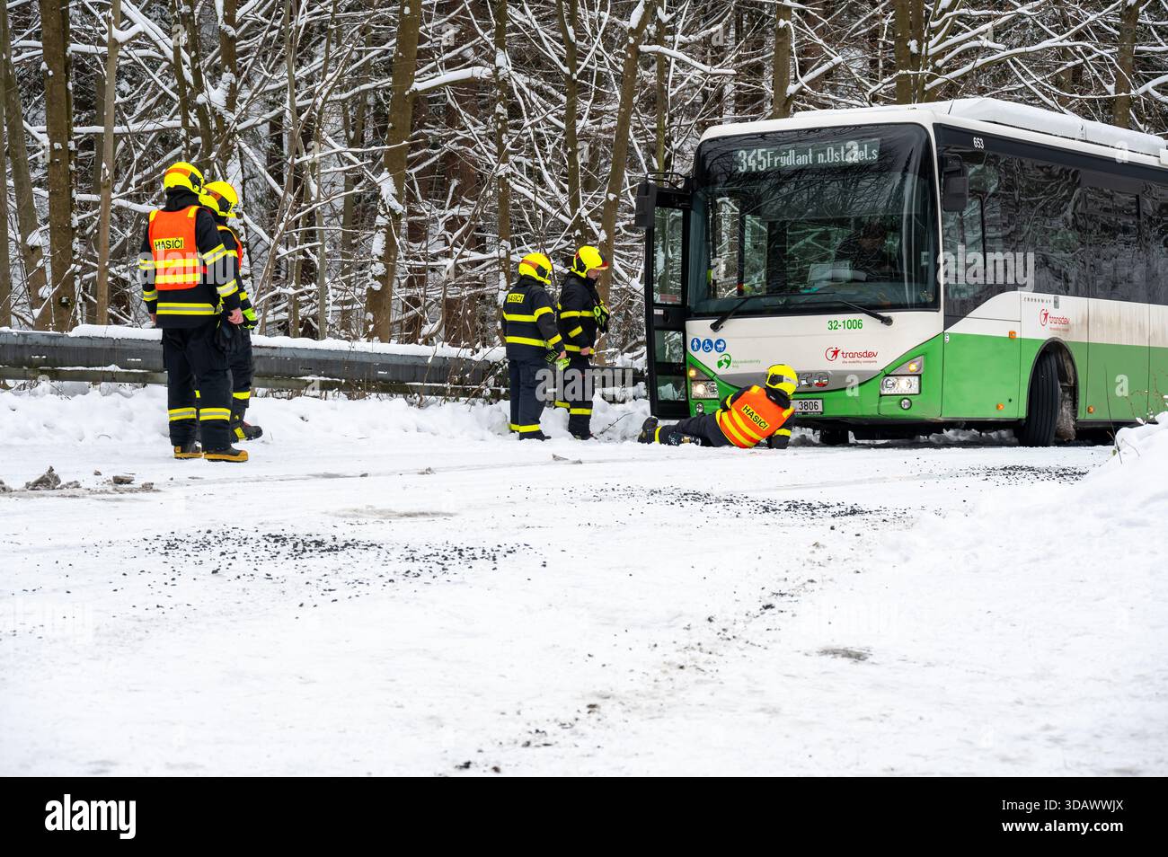 Ostrava, République tchèque - 23.11.2024, des pompiers travaillant pour libérer un bus coincé dans de profondes déneigements sur une route glacée et enneigée, capturant l'hiver c Banque D'Images