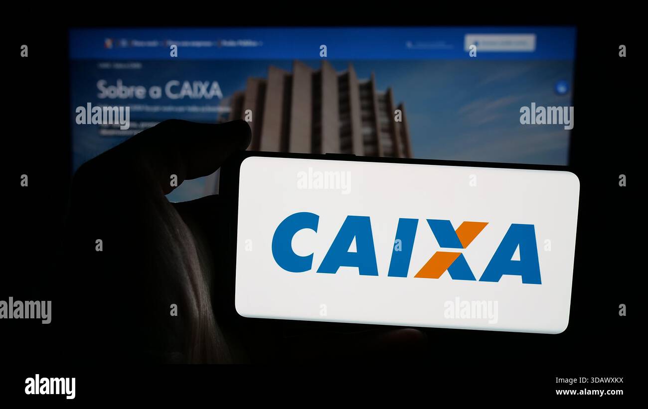 Stuttgart, Allemagne - 12-02-2025 : personne tenant un téléphone portable avec le logo de la brésilienne Caixa Economica Federal (CEF) sur l'écran devant la page web. Banque D'Images