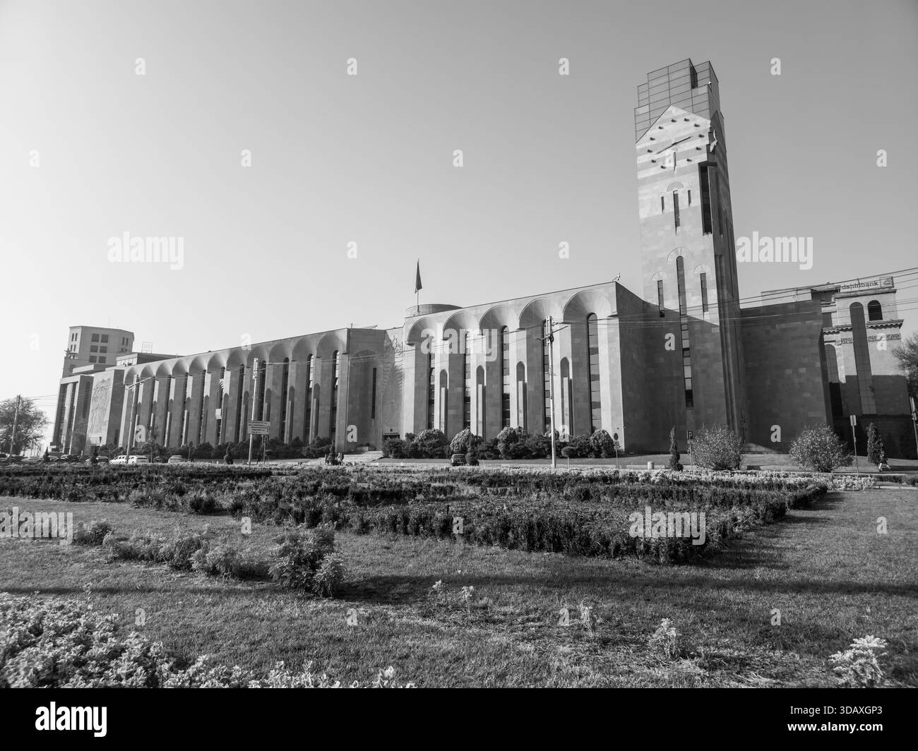 Erevan Arménie 12.5,2025. Un grand bâtiment de l'hôtel de ville avec une tour de l'horloge et un drapeau sur le dessus. Le bâtiment est entouré d'une zone herbeuse Banque D'Images