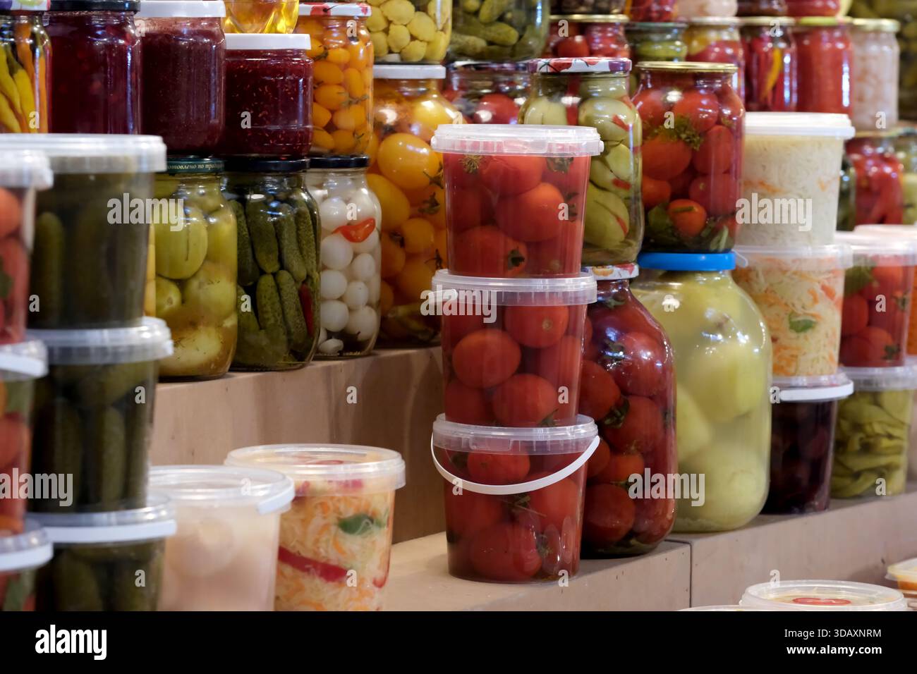 Des pots lumineux remplis de légumes marinés sont empilés dans une scène de marché animée. Kiev, Ukraine. 12 décembre 2025. Banque D'Images