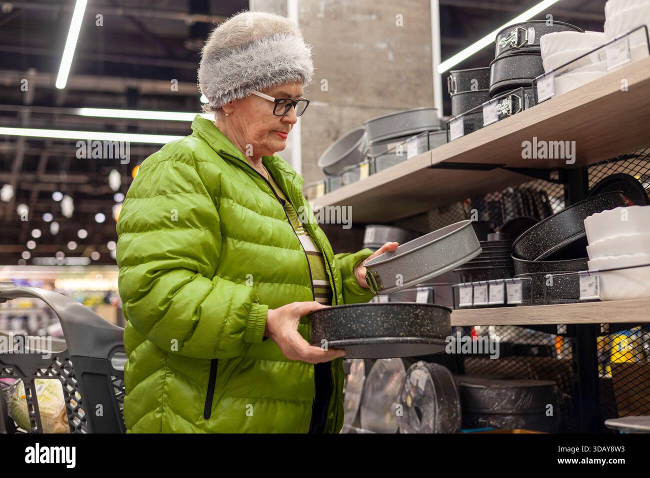 Femme âgée choisissant la plaque de cuisson dans la section des articles ménagers du supermarché. mode de vie senior actif, prise de décision quotidienne, sensibilisation au budget, cuisinier à la maison Banque D'Images