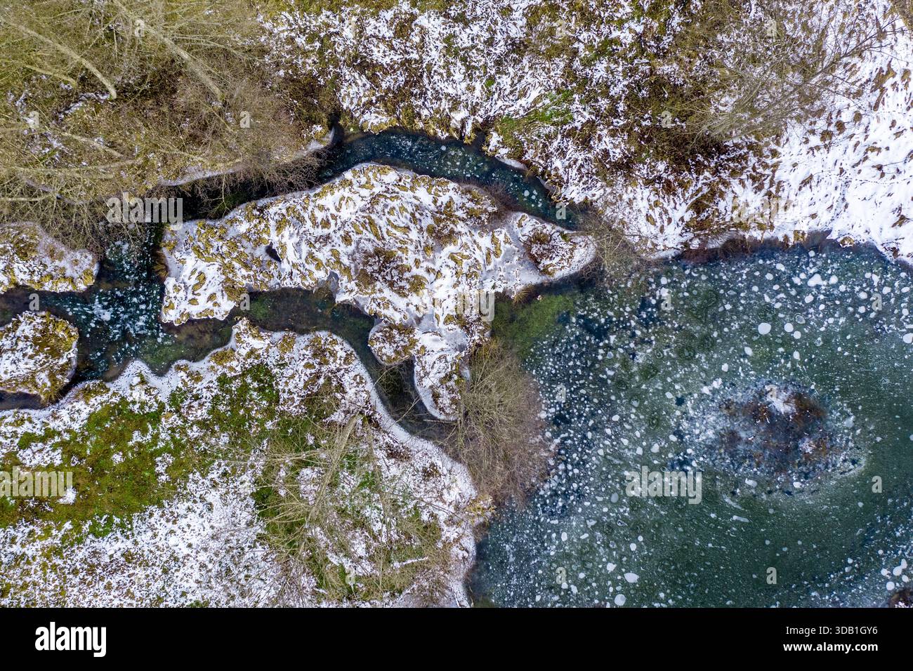 Vue hivernale du chenal gelé et du lac couvert de glace avec des berges poussiéreuses de neige dans la Forêt Noire, Allemagne Banque D'Images