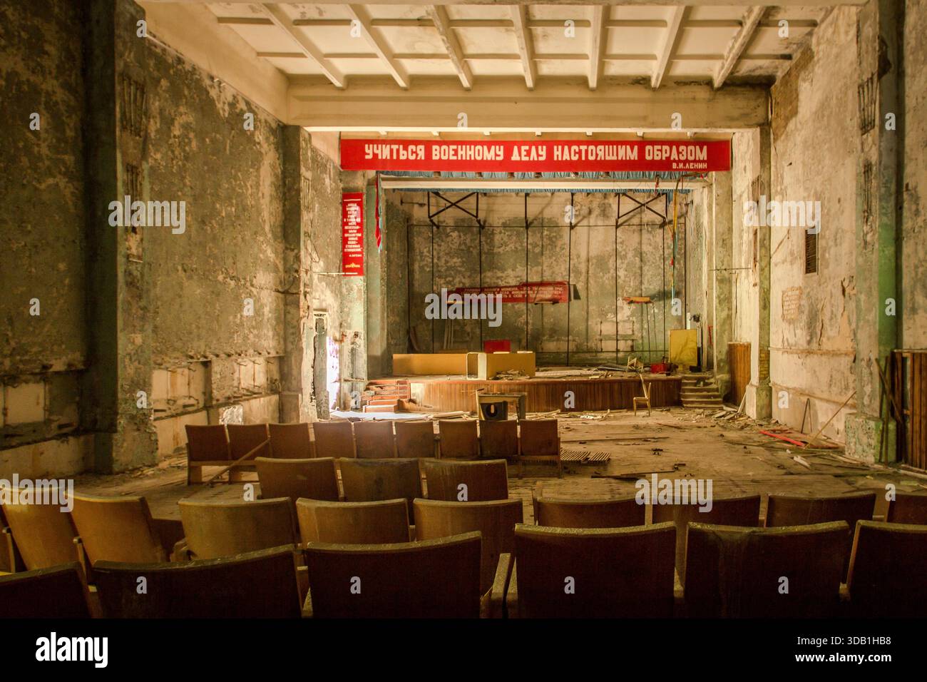 Auditorium scolaire soviétique abandonné avec murs en pelage, sièges vides et bannière de propagande Banque D'Images