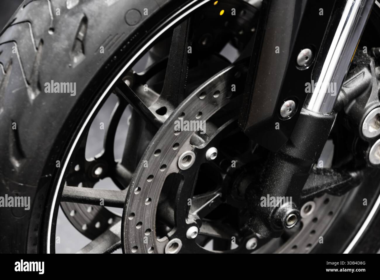 Vue rapprochée détaillée d'une roue avant de moto, frein à disque et fourches de suspension, vitesse de transport, puissance, et précision d'ingénierie idéale pour l'auto Banque D'Images