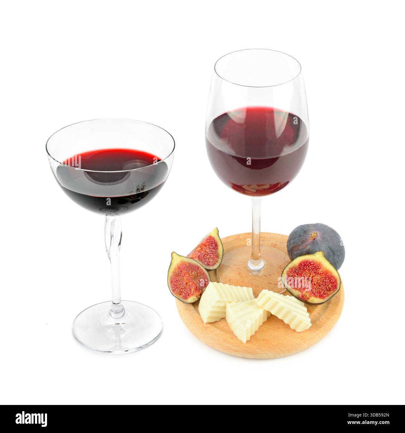 Deux verres de vin rouge sont présentés à côté d'une petite planche de bois contenant des figues tranchées et des morceaux de fromage gourmand. Banque D'Images