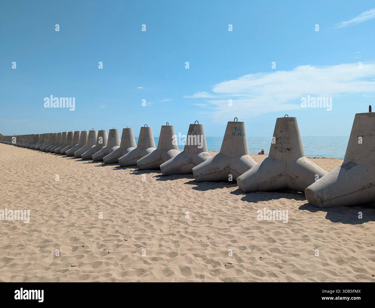Les tétrapodes massifs en béton reposent sur le sable près de la mer, leur structure durable mettant l'accent sur la force et la stabilité dans le contexte des vagues et Banque D'Images