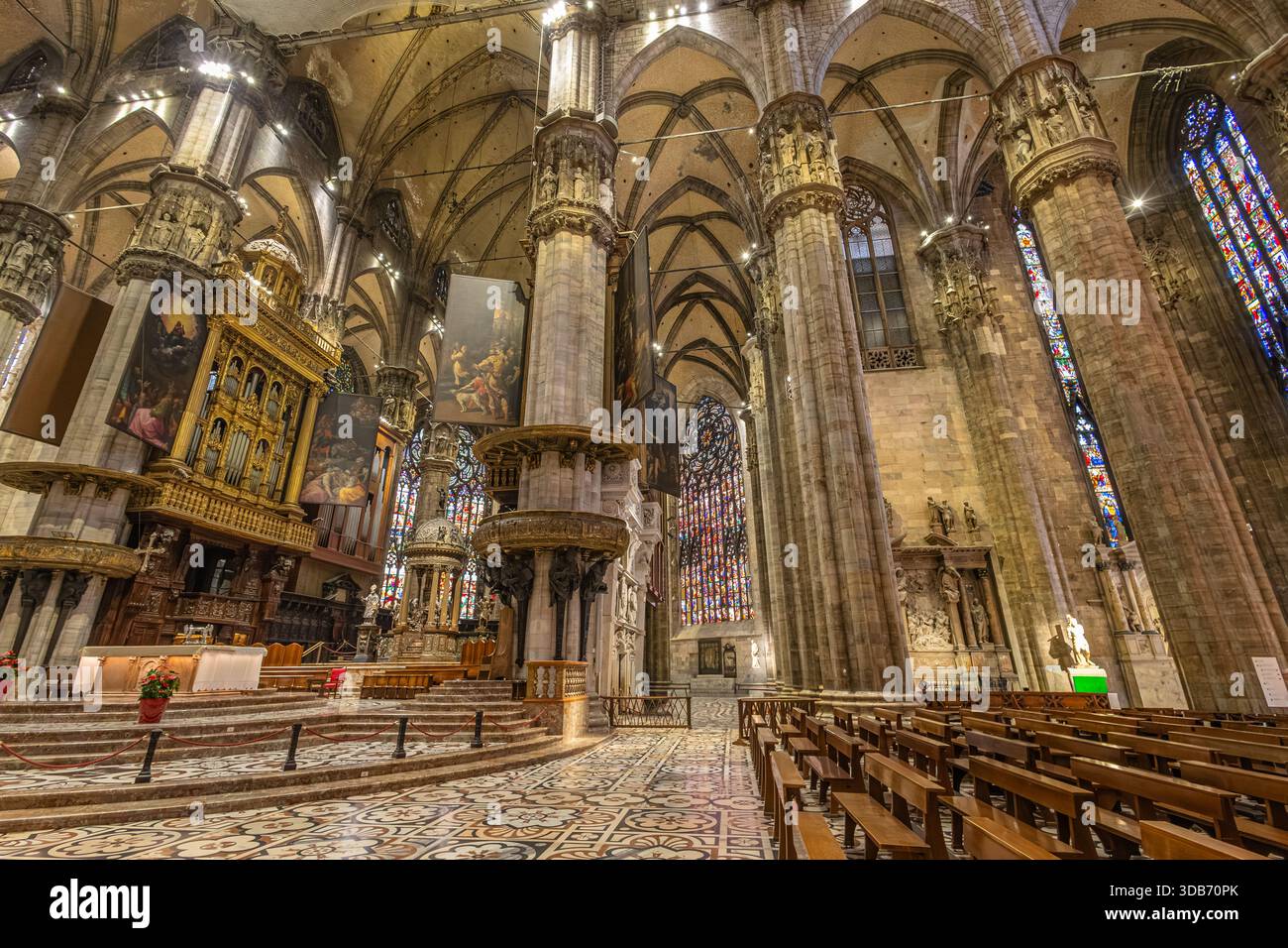 Un vaste intérieur gothique de cathédrale avec des colonnes imposantes, une chaire ornée et des vitraux colorés. L'architecture riche crée un sentiment d'admiration et de révérence Banque D'Images
