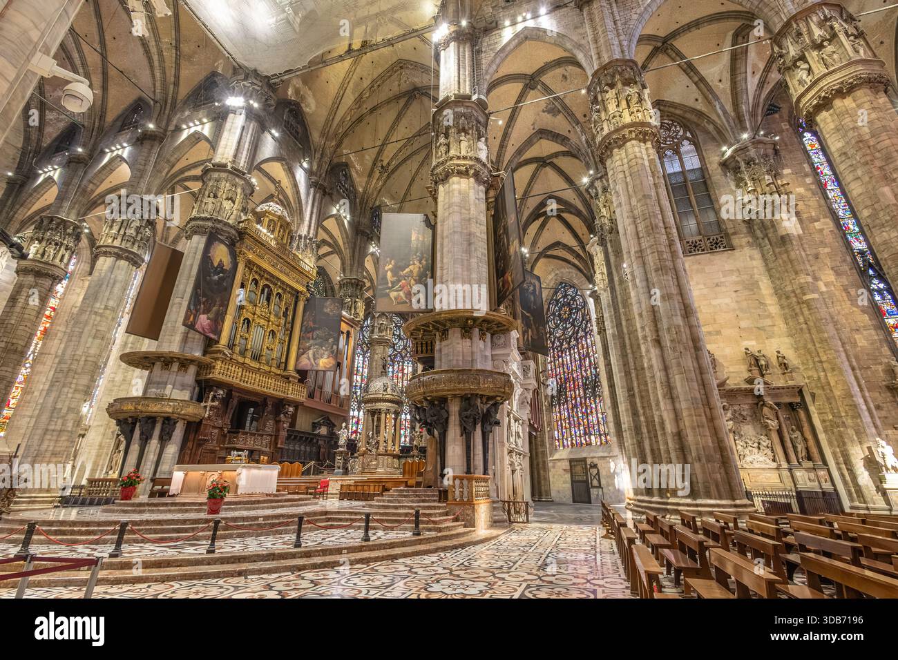 Un vaste intérieur gothique de cathédrale avec des colonnes imposantes, une chaire ornée et des vitraux colorés. L'architecture riche crée un sentiment d'admiration et de révérence Banque D'Images