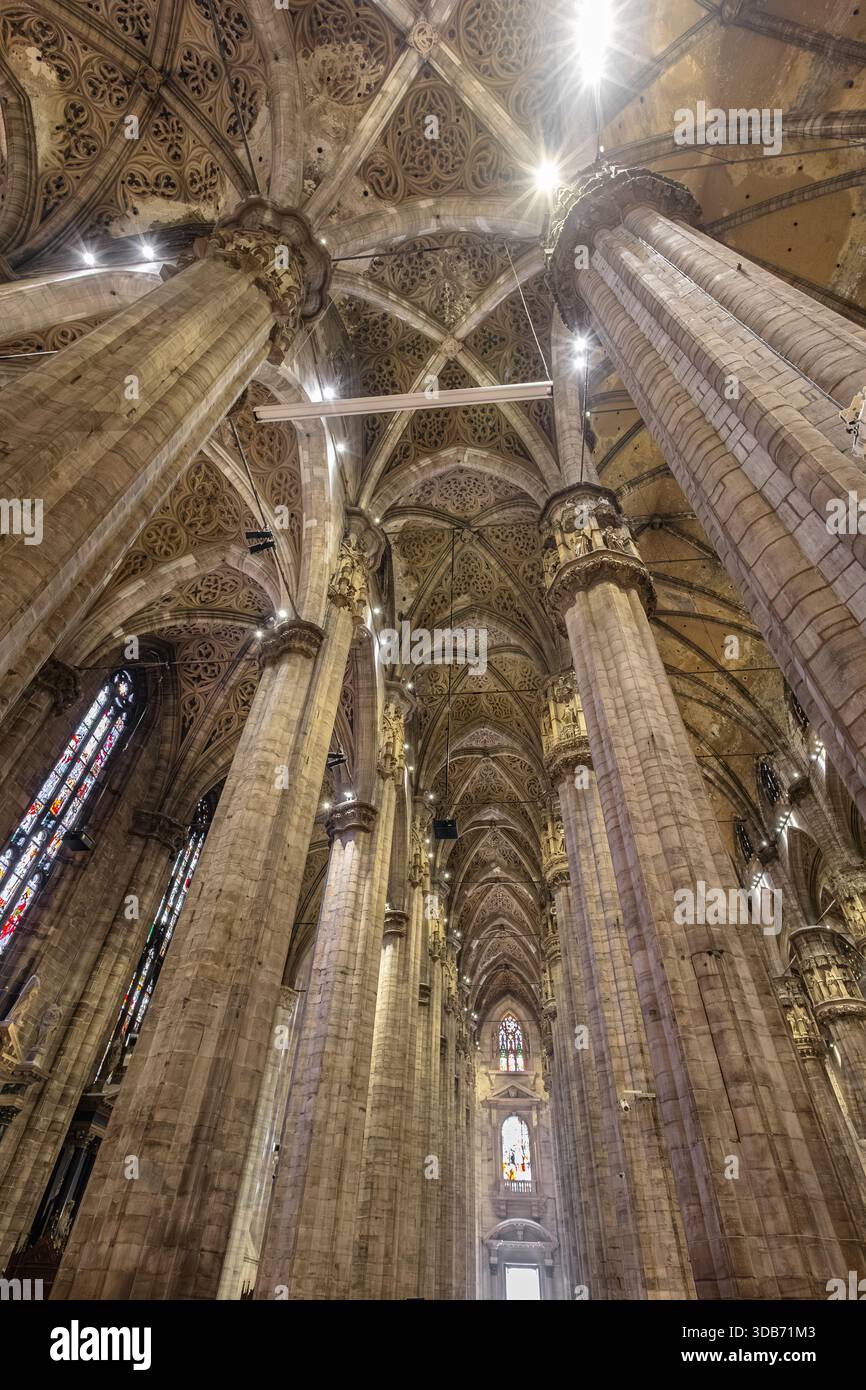 Un superbe intérieur gothique de cathédrale avec d'imposantes colonnes de pierre, des voûtes complexes et des vitraux colorés. L'architecture dramatique transmet Banque D'Images