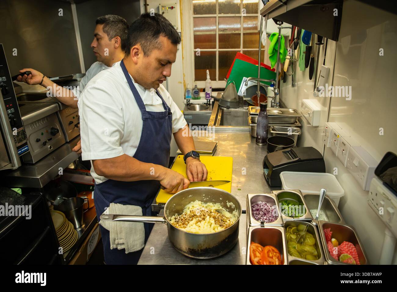 Cuisiniers préparant des aliments dans une cuisine de restaurant Banque D'Images