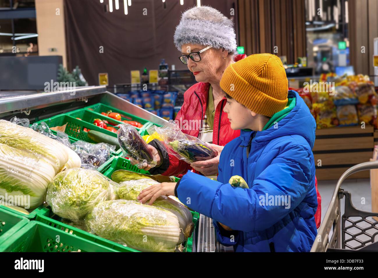 Grand-mère et petit-fils choisissant des légumes frais ensemble à la section des produits du supermarché. habitudes alimentaires saines, coopération intergénérationnelle, Banque D'Images