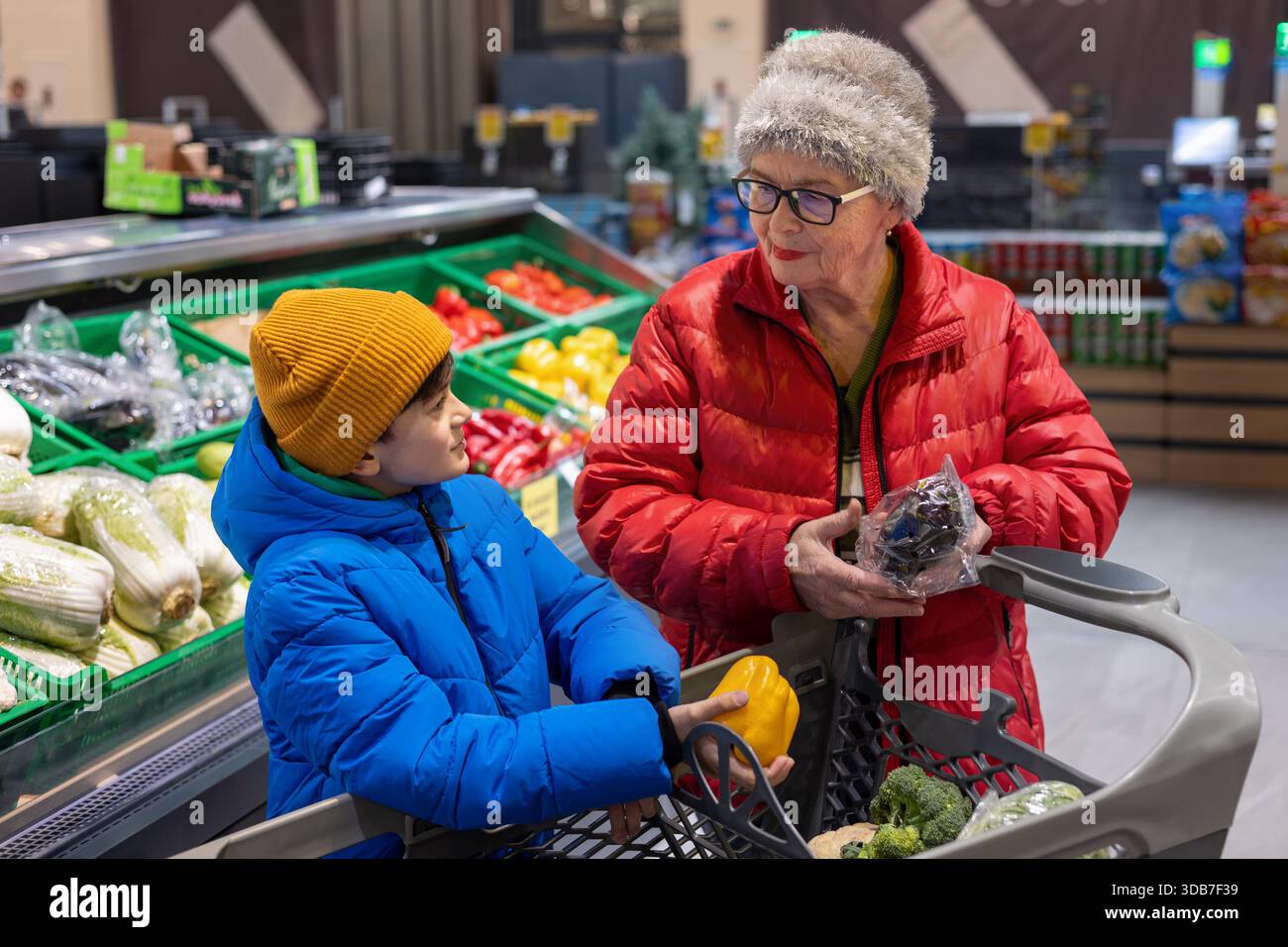 Grand-mère et petit-fils choisissant des légumes frais ensemble à la section des produits du supermarché. habitudes alimentaires saines, coopération intergénérationnelle, Banque D'Images