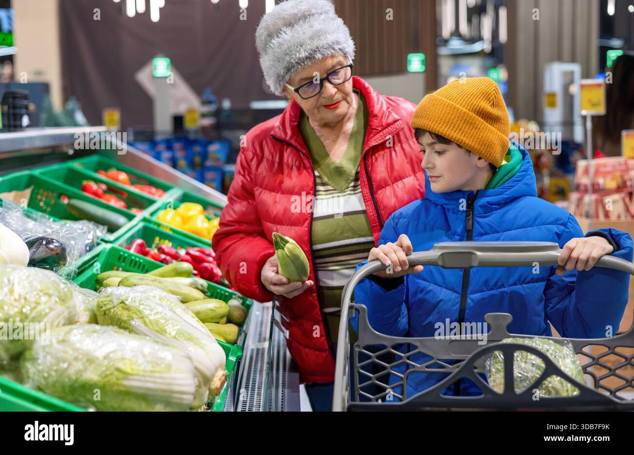Grand-mère et petit-fils choisissant des légumes frais ensemble à la section des produits du supermarché. habitudes alimentaires saines, coopération intergénérationnelle, Banque D'Images
