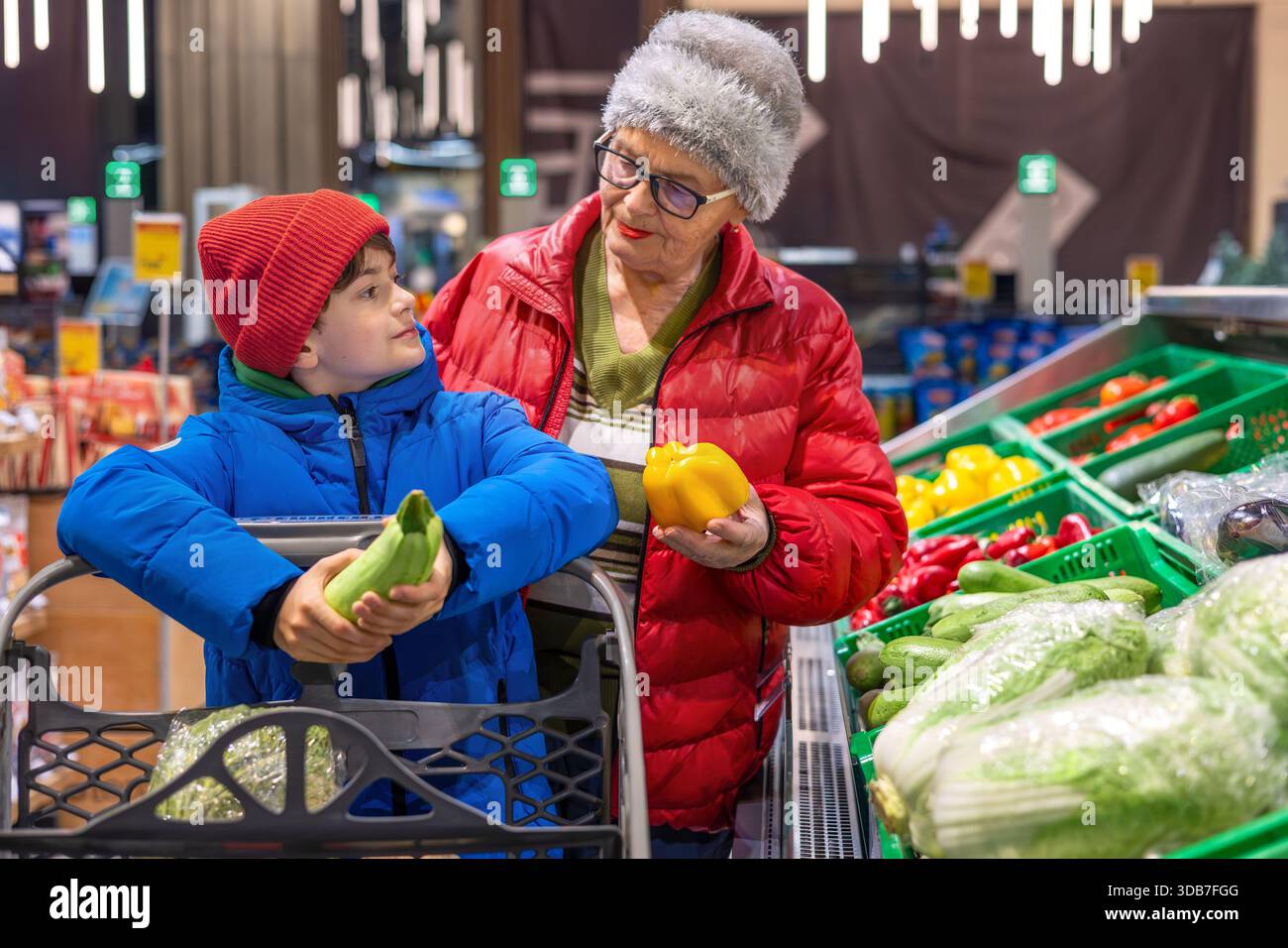 Grand-mère et petit-fils choisissant des légumes frais ensemble à la section des produits du supermarché. habitudes alimentaires saines, coopération intergénérationnelle, Banque D'Images