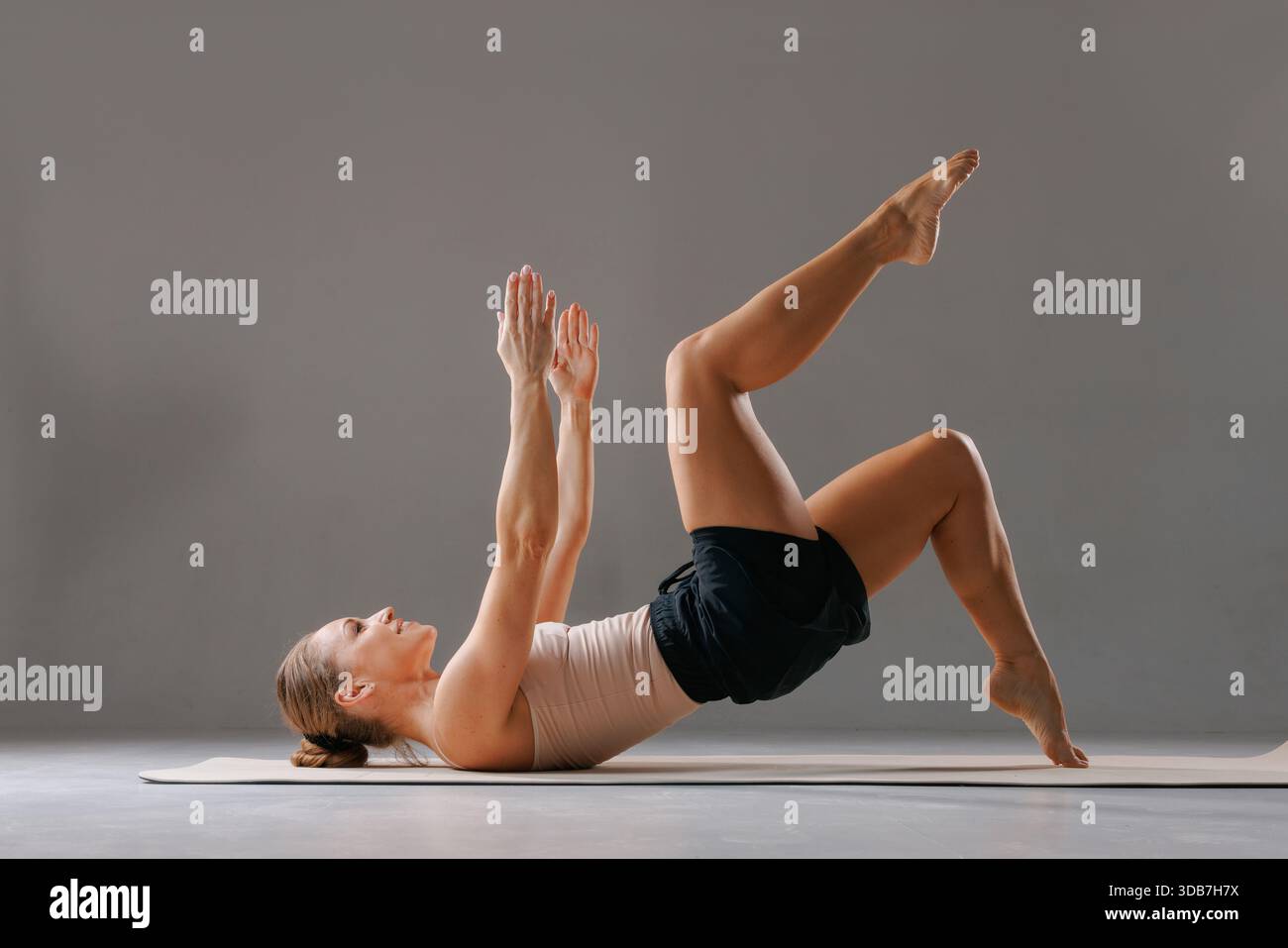 Femme en forme faisant le pont Pilates avec lifting des jambes, core et fessier entraînement sur tapis à l'intérieur. Banque D'Images