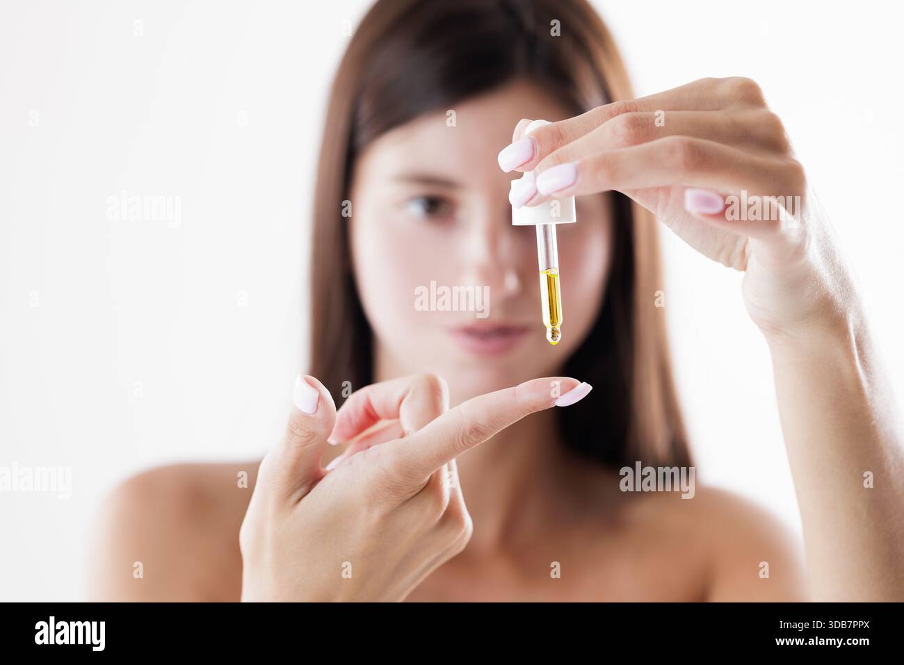 Jeune femme appliquant le sérum facial avec un compte-gouttes, routine de soins de la peau, traitement de beauté, peau éclatante, concept d'auto-soins Banque D'Images