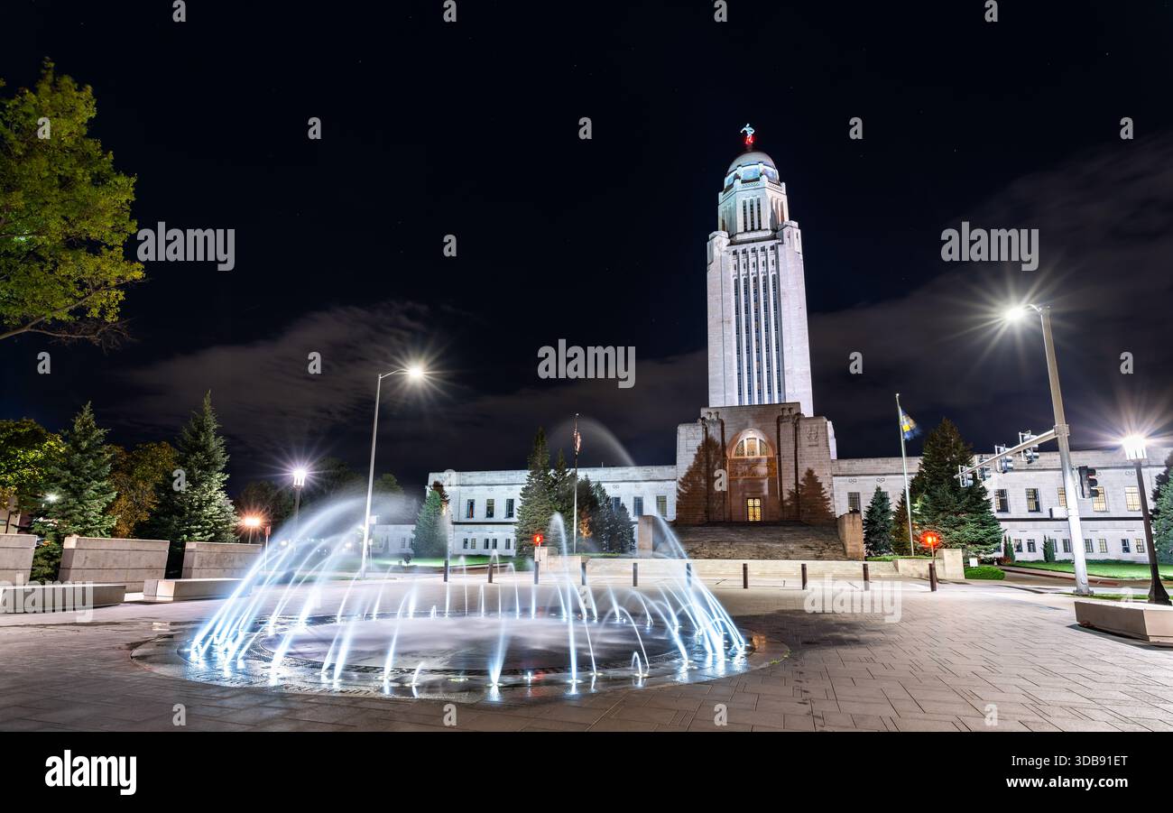 Vue nocturne du Capitole de l'État du Nebraska à Lincoln, États-Unis. Limestone Tower of the Plains présente un dôme doré et une statue de Sower derrière des fontaines illuminées Banque D'Images