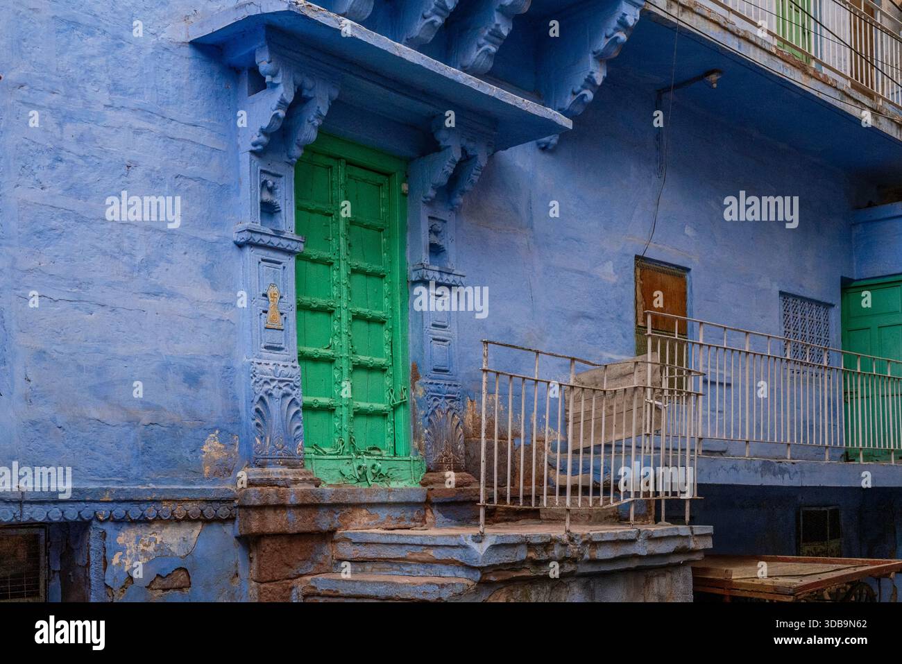 Une porte verte de la ville bleue de Jodhpur, Rajasthan, Inde, avec ses maisons bleues emblématiques Banque D'Images