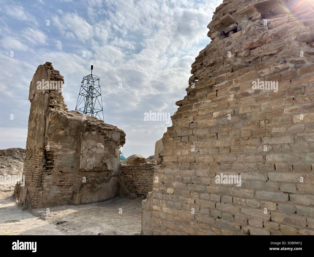Ruines de briques anciennes encadrant la tour moderne contre le ciel lumineux et nuageux Banque D'Images