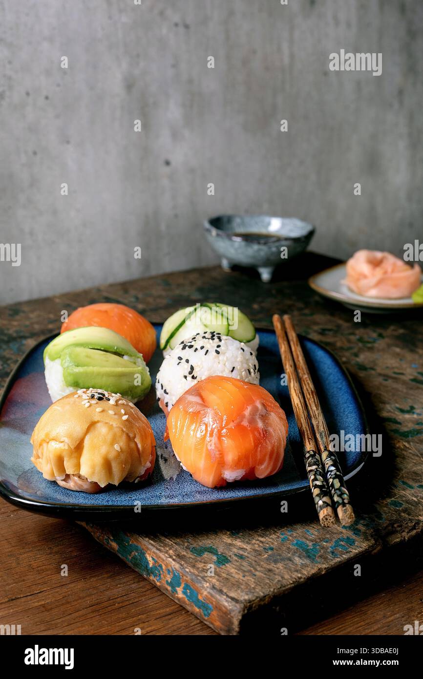 Temari sushi. Boules de sushi tendance avec saumon, avocat, concombre et omelette japonaise sur assiette bleue. Sauce soja, gingembre mariné, baguettes sur WO rustique Banque D'Images
