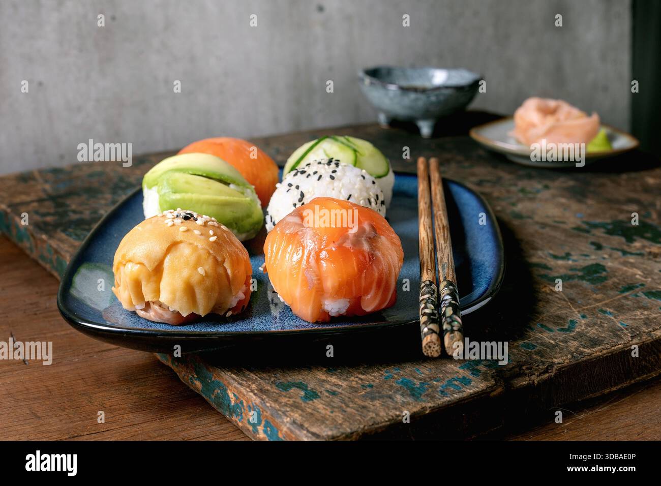 Temari sushi. Boules de sushi tendance avec saumon, avocat, concombre et omelette japonaise sur assiette bleue. Sauce soja, gingembre mariné, baguettes sur WO rustique Banque D'Images