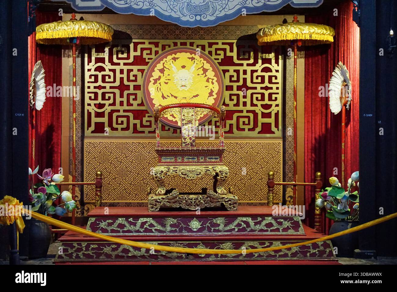 Salle du trône impérial, Vietnam - trône de dragon doré orné, rideaux rouges, parapluies cérémoniels et motifs traditionnels. Banque D'Images