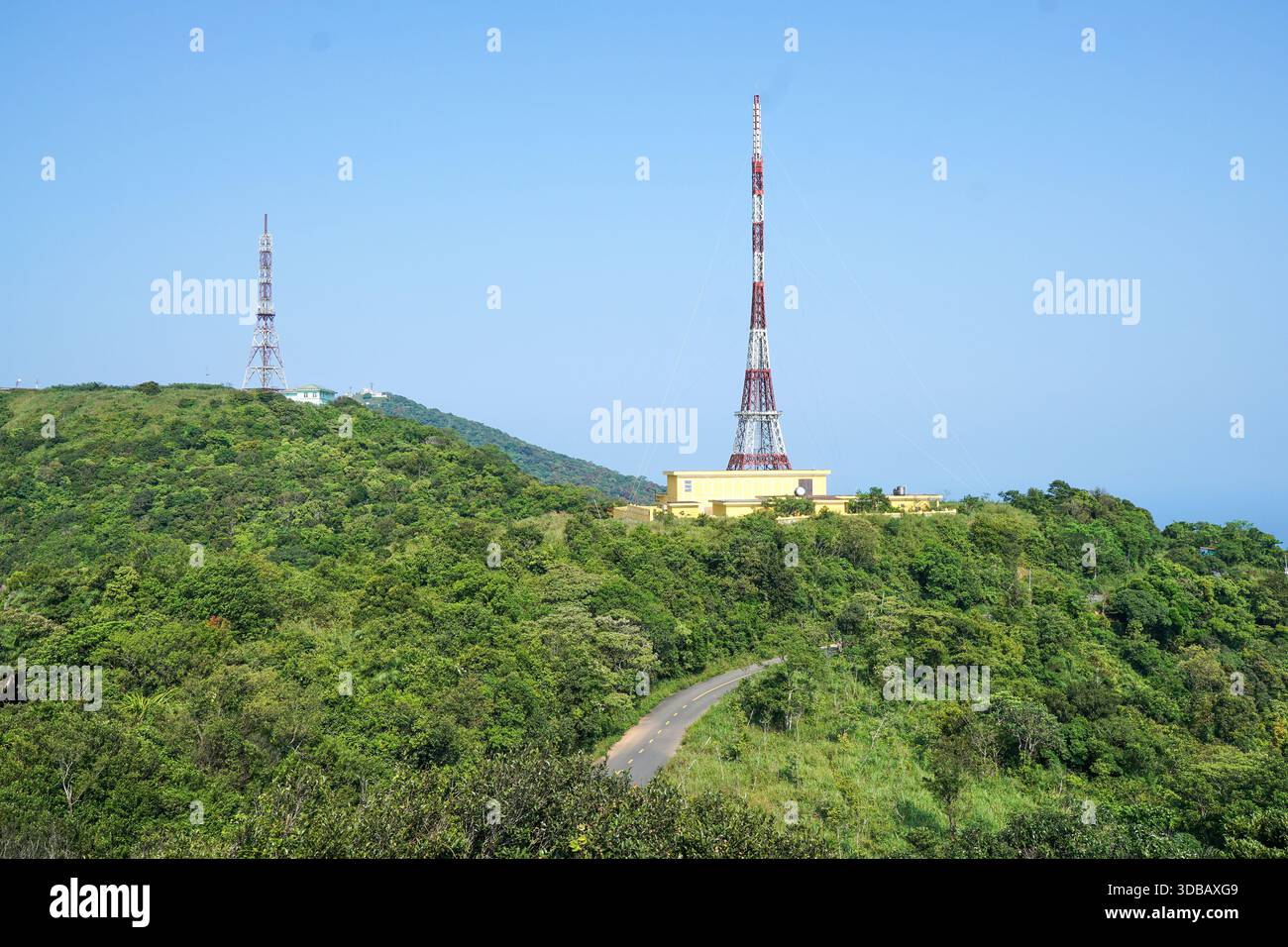 Deux tours de communication se dressent sur une montagne verdoyante sous un ciel bleu clair. Banque D'Images