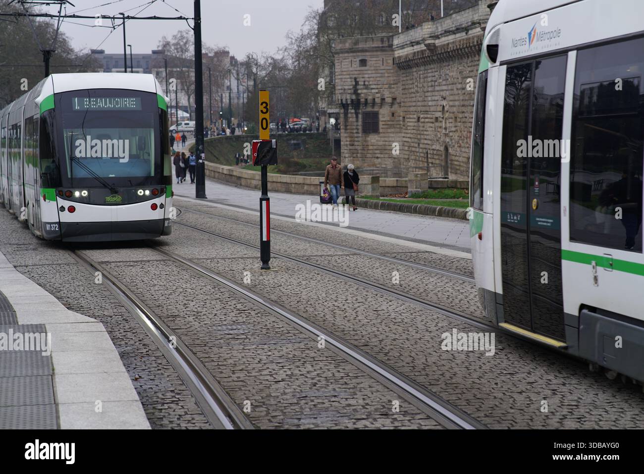 Tramway moderne à plancher surbaissé arrivant à un arrêt dans le centre-ville de Nantes, France, montrant les transports publics urbains quotidiens dans une ville européenne. Nantes Banque D'Images