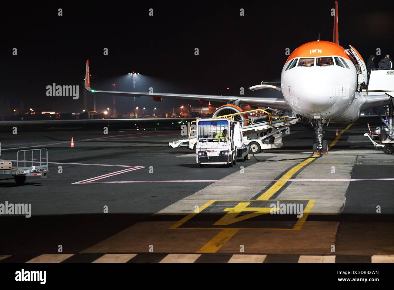 Avion de passagers sur l'aire de trafic de l'aéroport la nuit avec des véhicules terrestres et l'équipage préparant le vol.Nantes, France Banque D'Images