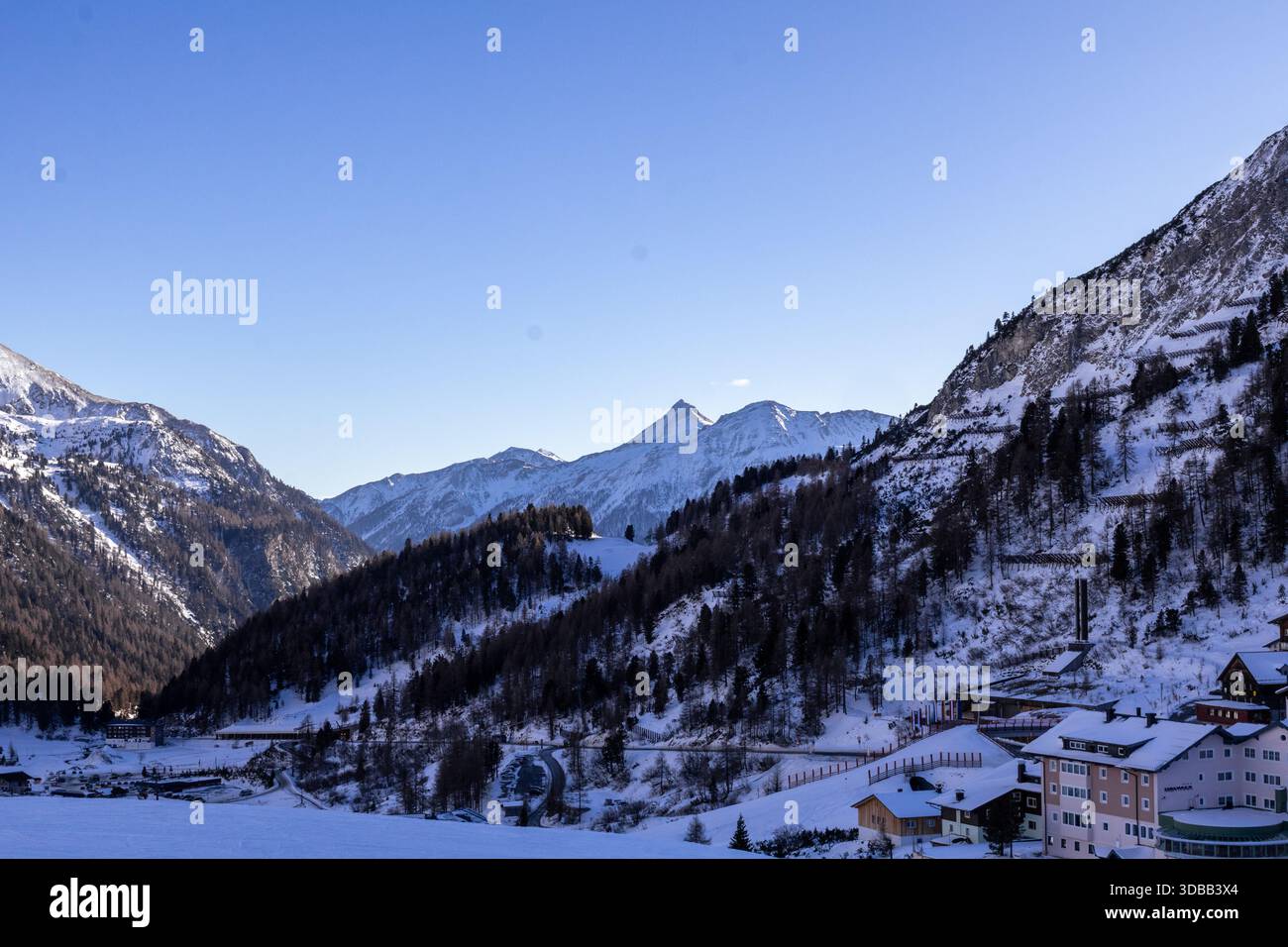 Une vue pittoresque sur un village enneigé niché dans les Alpes autrichiennes. Des chalets et des hôtels traditionnels bordent la vallée, recouverts d'une épaisse couche Banque D'Images