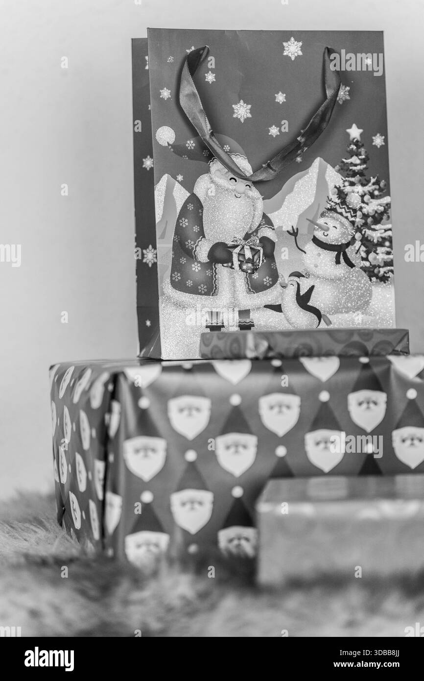 Une image en noir et blanc gros plan de cadeaux de Noël enveloppés dans des décorations festives Banque D'Images