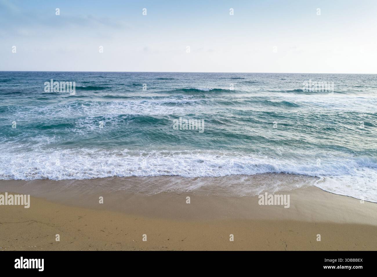 Vue aérienne des vagues turquoises embrassant doucement le sable doré sous un ciel doux, Vrachos, Preveza, Grèce. Banque D'Images