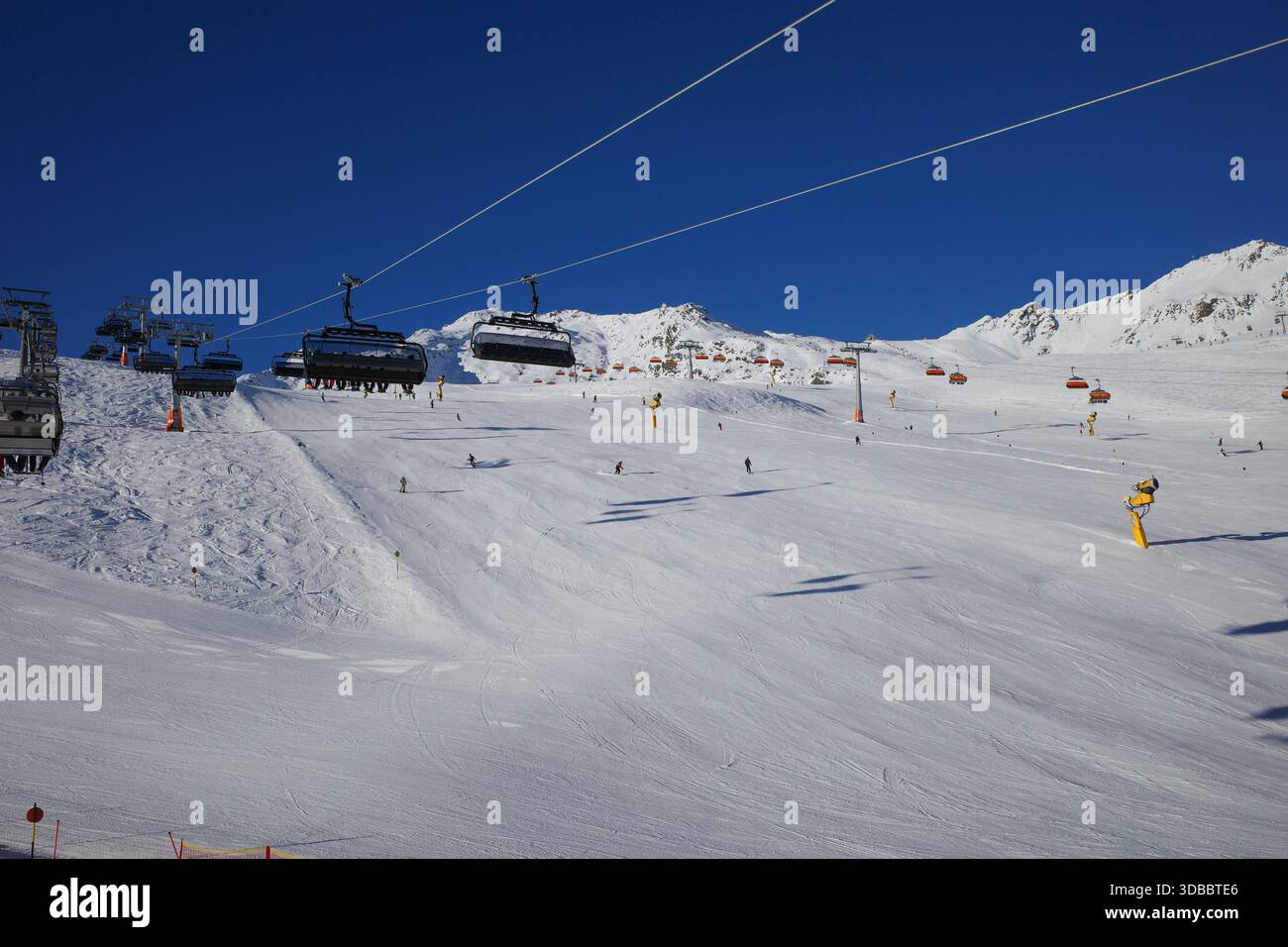 Un paysage hivernal pittoresque dans une station de ski alpin moderne avec télésièges, skieurs et pistes de montagne enneigées sous un ciel bleu clair. Ce salut Banque D'Images