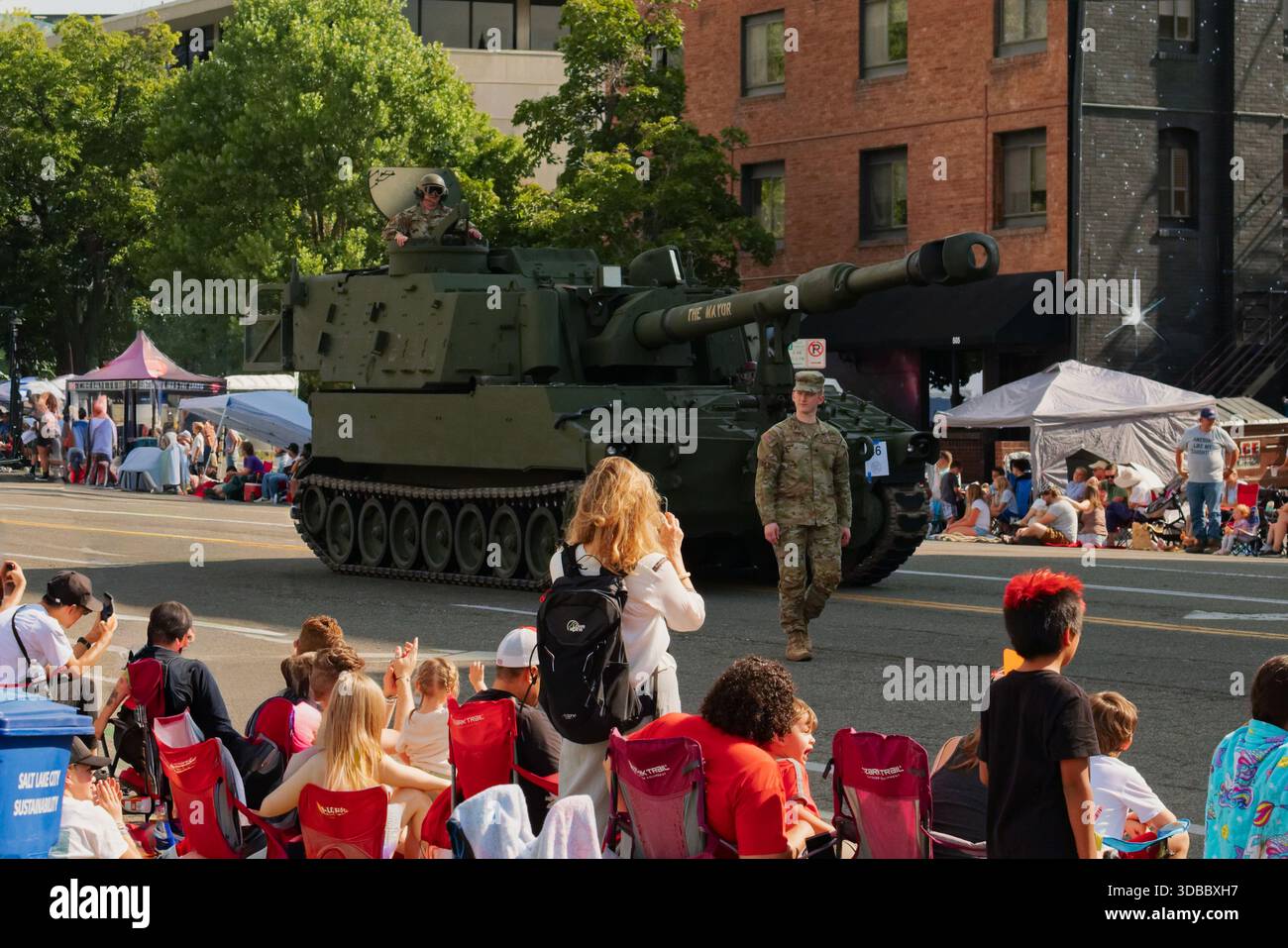 Les gens regardent un défilé militaire avec un char et des soldats dans une rue de la ville Banque D'Images