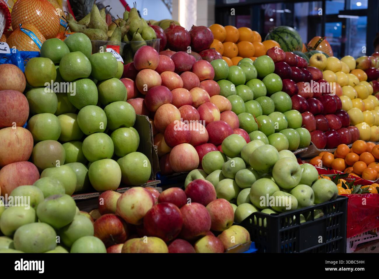 Présentation pyramidale colorée de pommes fraîches dans différentes nuances de vert, rouge, jaune, oranges, grenades et poires sur un étal de marché aux fruits. Banque D'Images