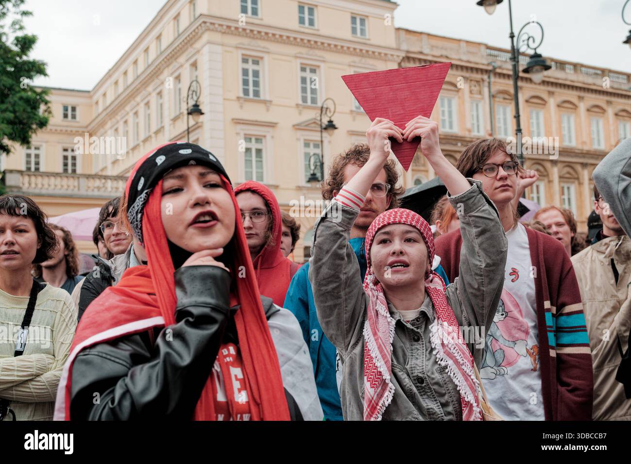 Étudiant levant le triangle rouge lors d'un rassemblement pro-palestinien près de l'entrée de l'Université de Varsovie. Banque D'Images
