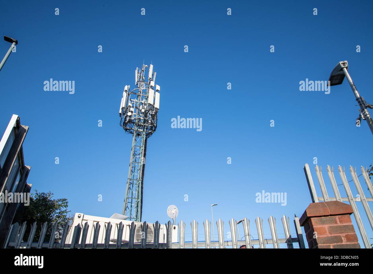 Un haut mât de téléphone portable capturé contre un ciel bleu clair, montrant l'infrastructure de réseau cellulaire moderne et l'équipement de télécommunications. Banque D'Images