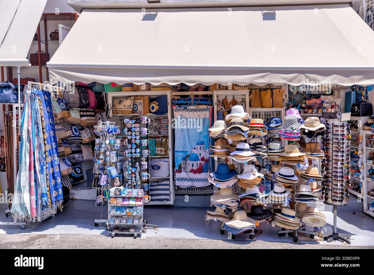 Boutique de souvenirs vendant des chapeaux et des foulards le long d'une rue piétonne à Santorin, en Grèce, populaire auprès des visiteurs de croisière. Banque D'Images