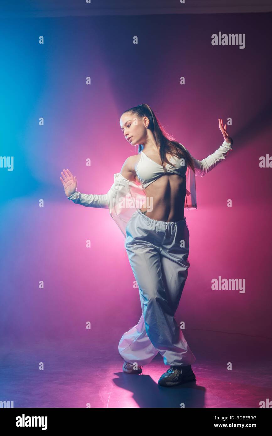 Portrait pleine longueur de jeune femme posant dans le style hip hop funk néon jazz avec lumière bleue et rose pour la discothèque et la promotion de la danse Banque D'Images