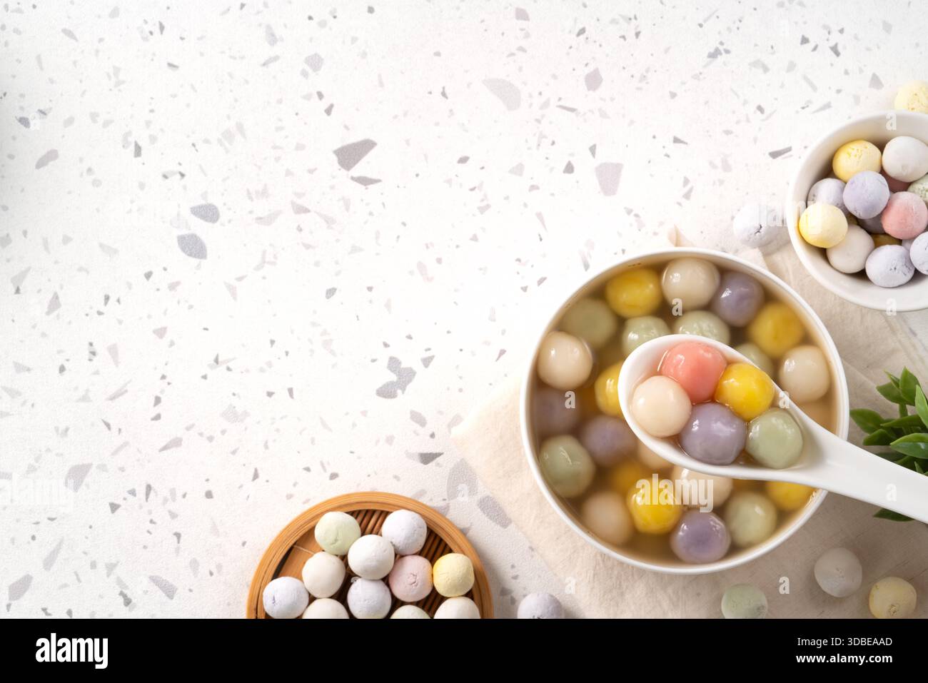 Soupe sucrée asiatique traditionnelle avec des boulettes de riz gluant colorées tangyuan servies dans du sirop de gingembre doux chaud sur fond de terrazzo blanc Banque D'Images