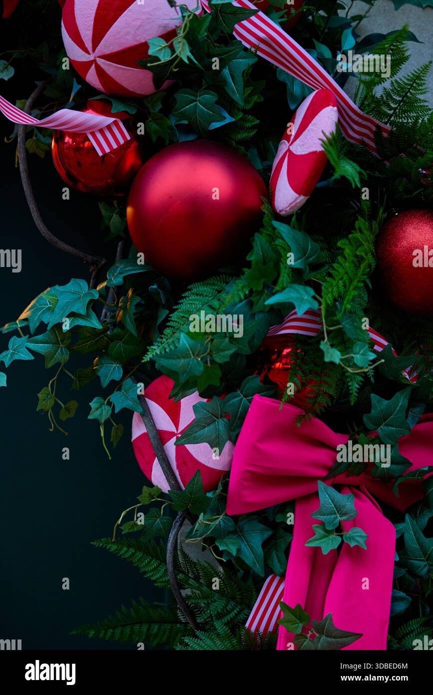 Décorations de Noël en forme de couronne à feuilles persistantes, rubans et détails saisonniers, symbolisant les fêtes hivernales festives. Banque D'Images