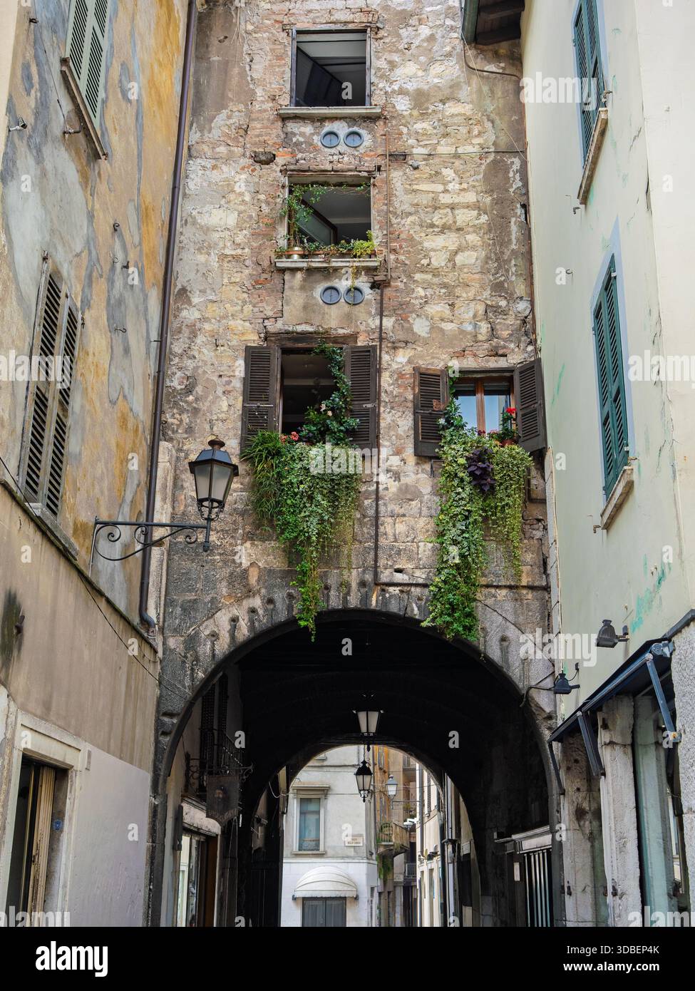 Ruelle pavée avec Stone Archway et fenêtres envahies au-dessus, Brescia, Italie. Banque D'Images