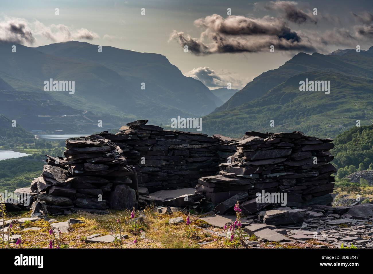 Ruine d'abri en ardoise à la carrière d'ardoise de Glyn Rhonwy surplombant une vallée de montagne sous des nuages spectaculaires Banque D'Images