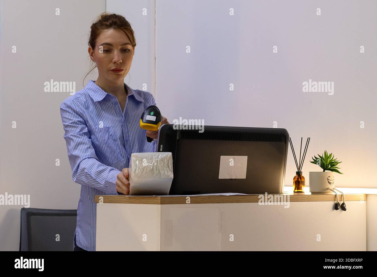 Le personnel utilise un lecteur de codes-barres sur l'article emballé placé sur le bureau avec l'ordinateur Banque D'Images