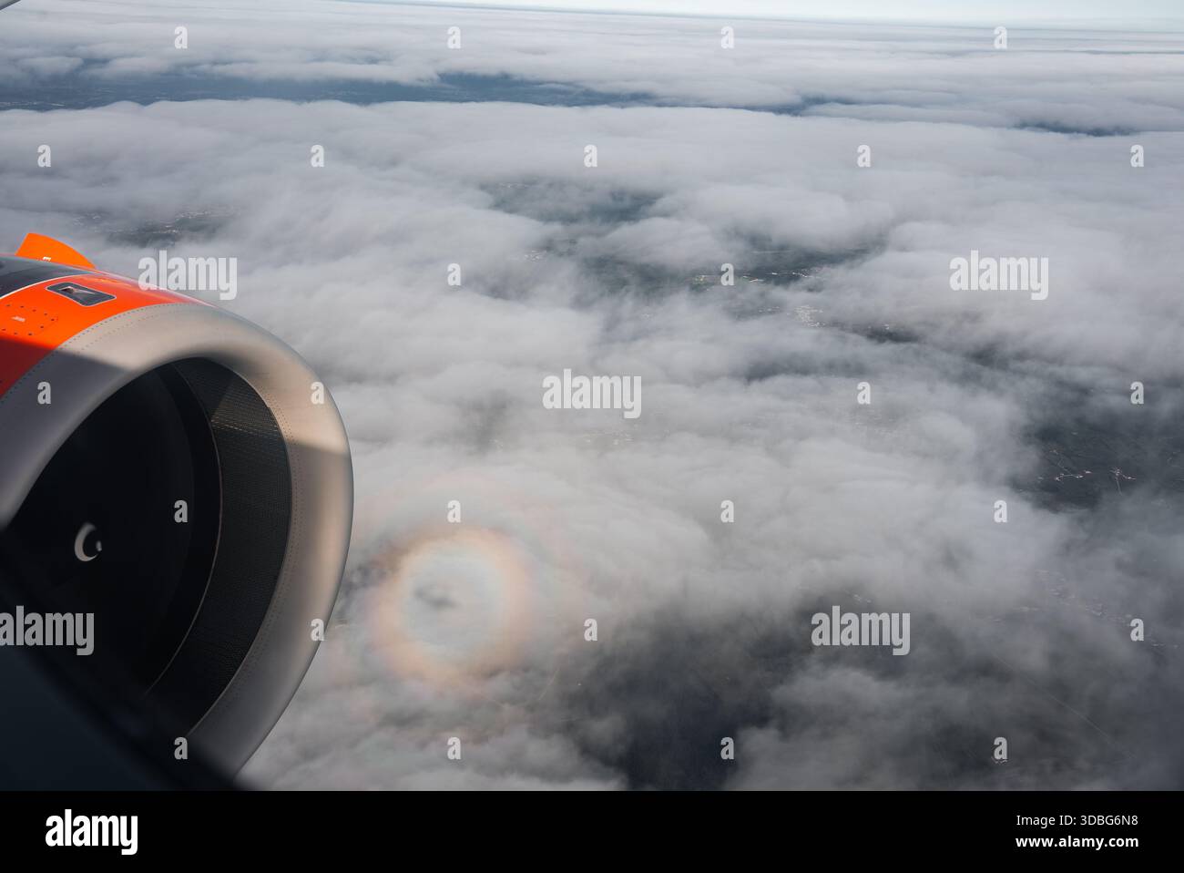 La vue aérienne montre un moteur d'avion orange, des nuages stratiformes, et une gloire près de Funchal, Madère. Un paysage pâle montre à travers des lacunes sous doux, diffu Banque D'Images