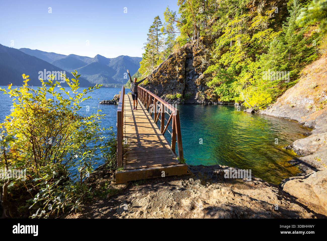 Une jeune fille heureuse est capturée debout sur le pont Punchbowl du Diable, en admirant le site pittoresque de Lake Crescent dans le parc national olympique, Willing Banque D'Images